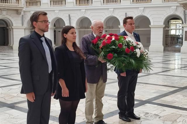 Zdjęcie osób skladających kwiaty pod tablicami w Gmachu Głównym Politechniki Warszawskiej