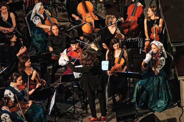 Zdjęcie przedstawia osoby grające na instrumentach podczas koncertu