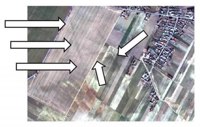 Zdjęcie pól z dużej wysokości z miejscami występowania elementów osadnictwa zaznaczonymi strzałkami.
