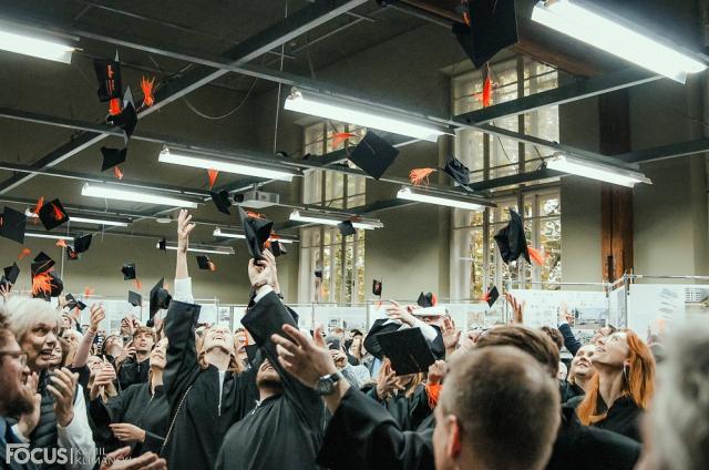 Zdjęcie przedstawia podrzucone czapki absolwentów